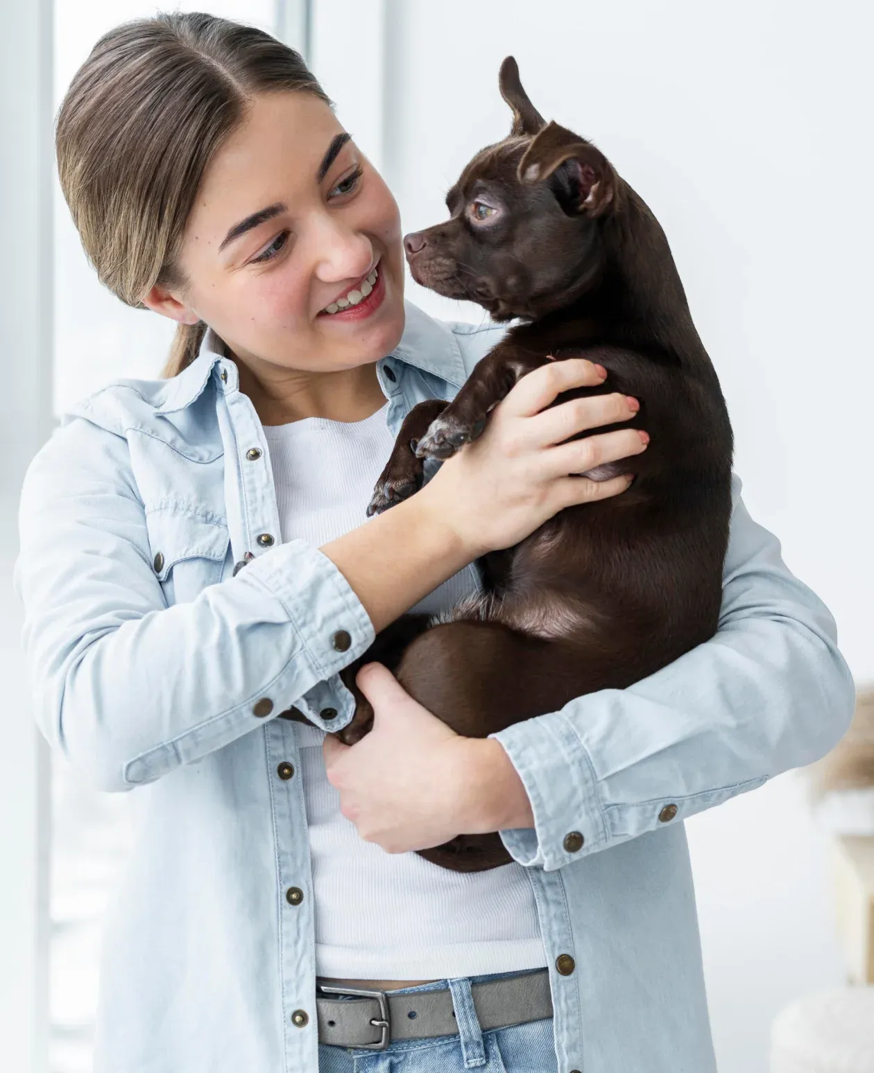 Smiling woman holding a small brown dog
