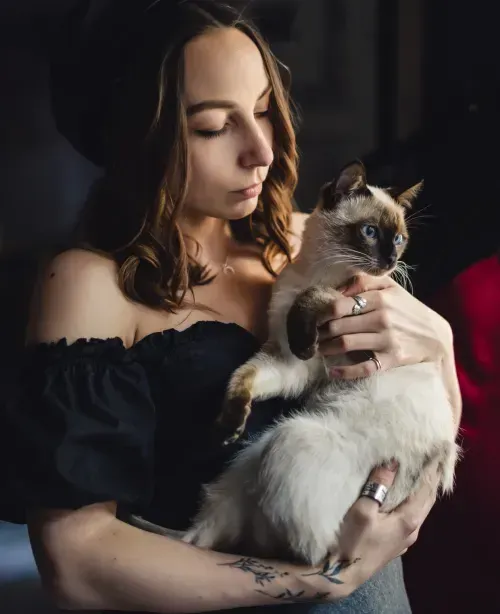 Woman cradling a siamese cat